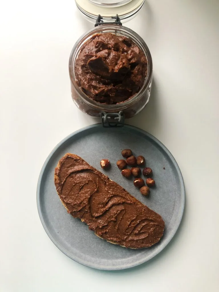 Hazelnut spread in a small jar and also spread in a slice of bread