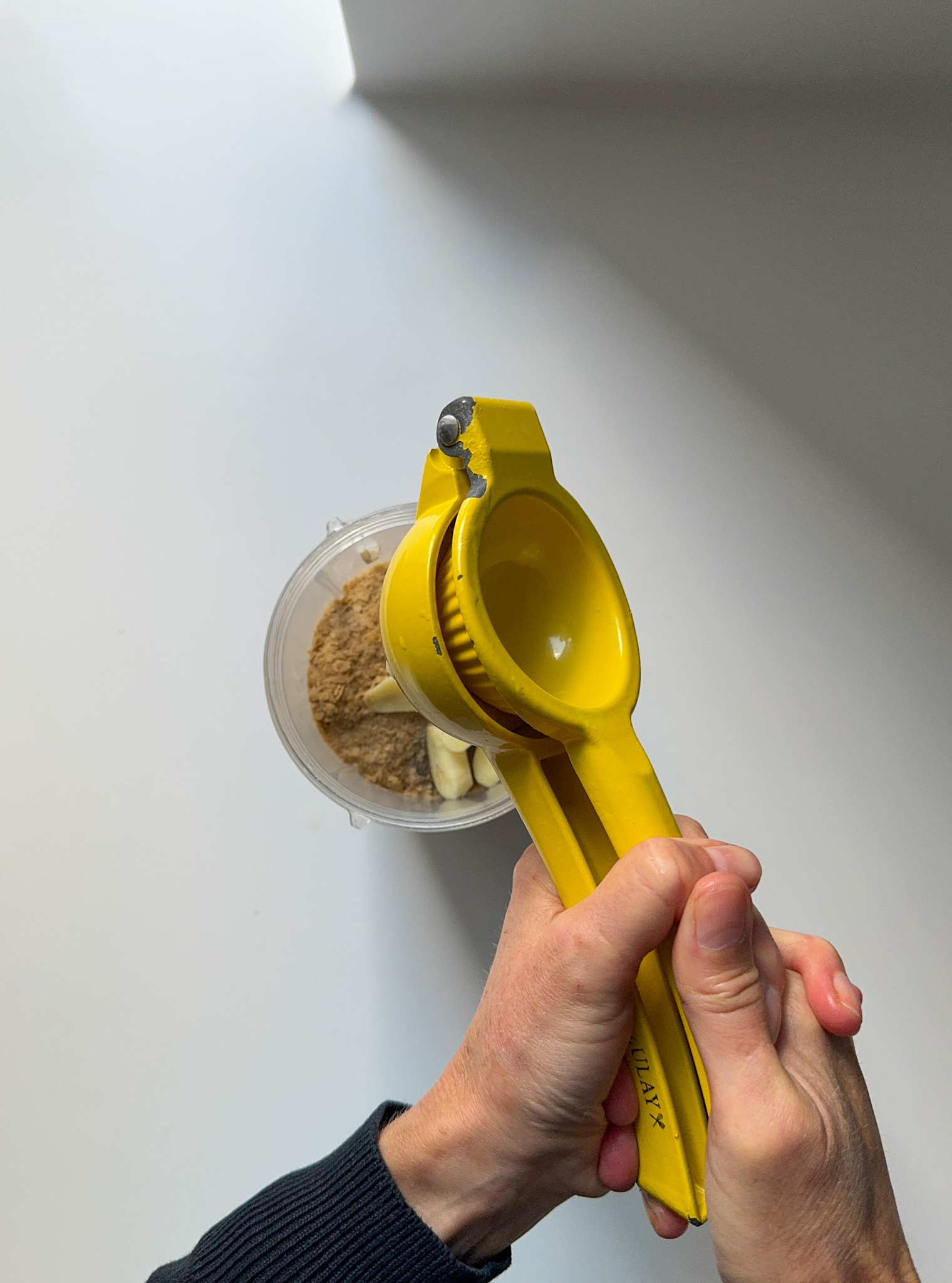 Lemon being squeezed on top of cashews, species on a blender container