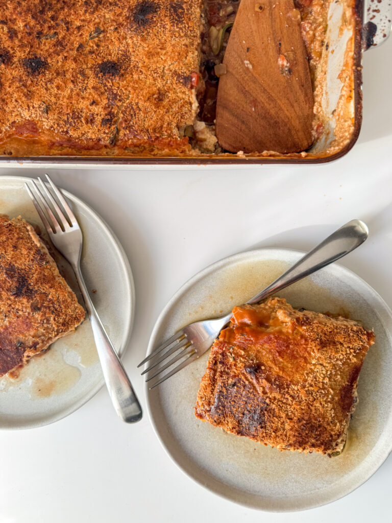 A trey of lasagne with 2 Squares of lasagne on 2 small plates ready to eat