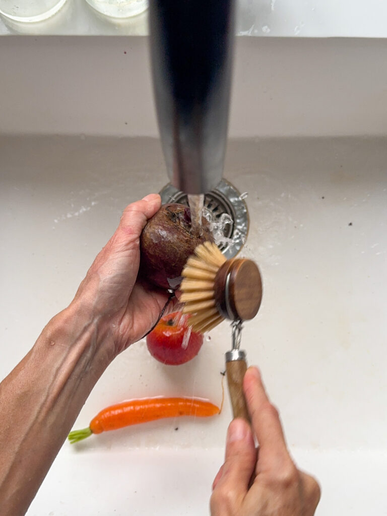 Washing one Beetroot, one apple and one carrot.