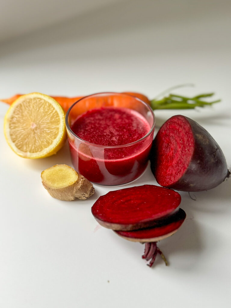 Beetroot Juice in a Glass surround by Beetroot, carrot, lemon and ginger