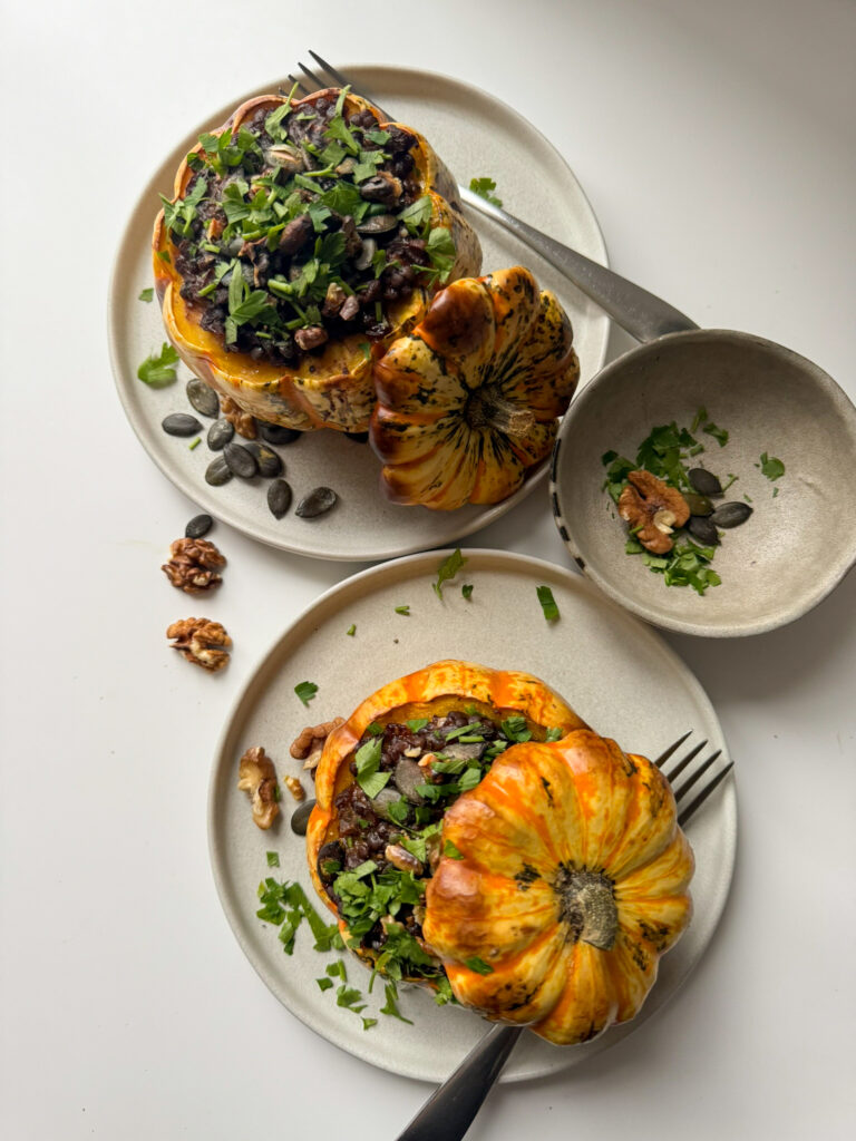 2 roasted pumpkins, stuffed with smoked beluga lentils in 2 small plates springle with parsley from above