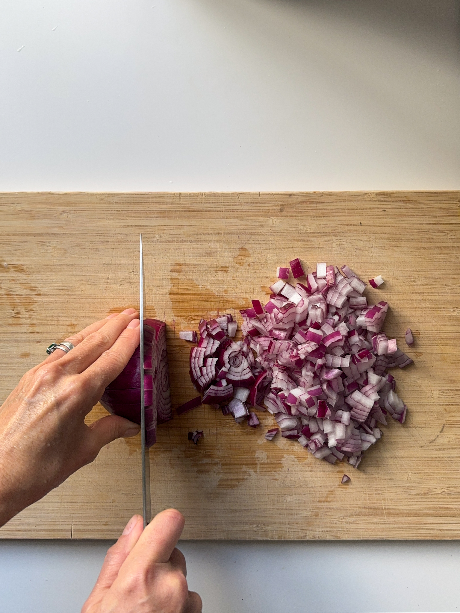 A red onion being finely chopped on a wood board