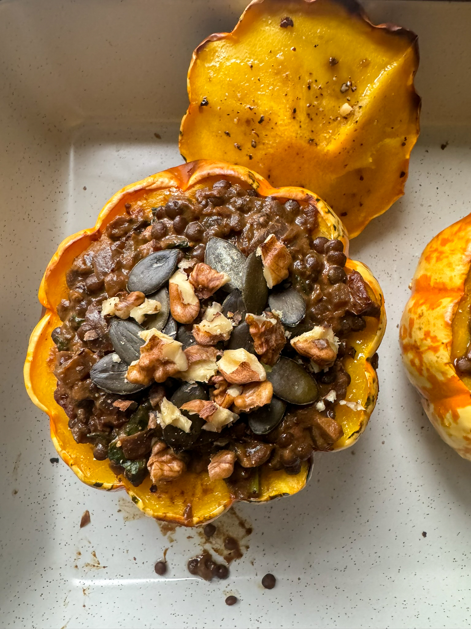 Roasted pumpkin stuffed with smoked beluga lentils topped with pumpkin seeds and walnuts