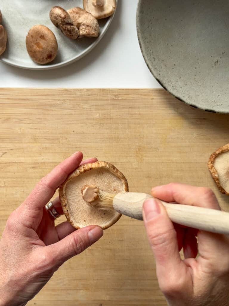 Shiitake mushrooms being clean with a brush