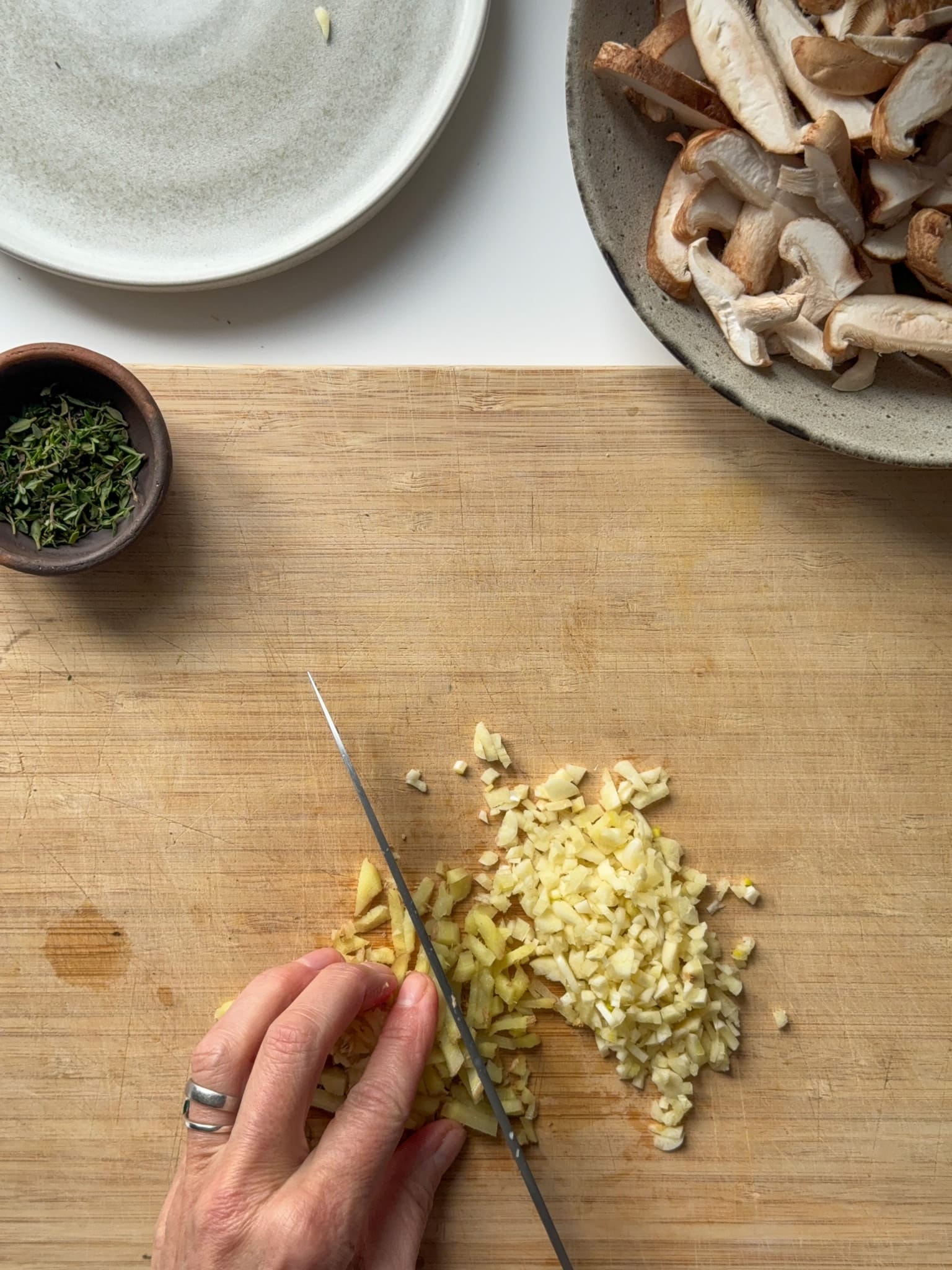 Chopping Garlic and ginger, shiitake mushrooms cutted on the top right and thyme leaves in a little vase