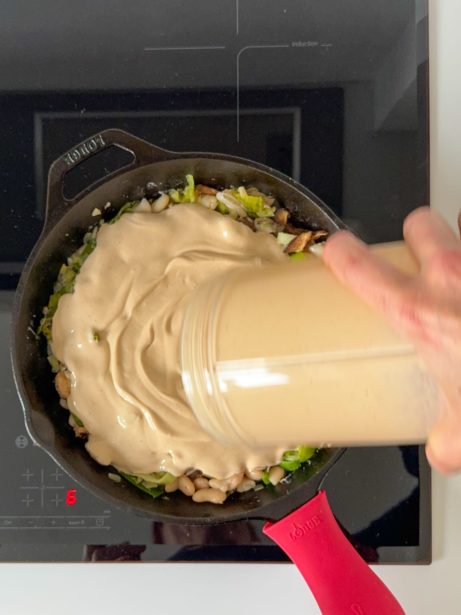 Tofu cheese mixture being add to sauté leeks and butter beans