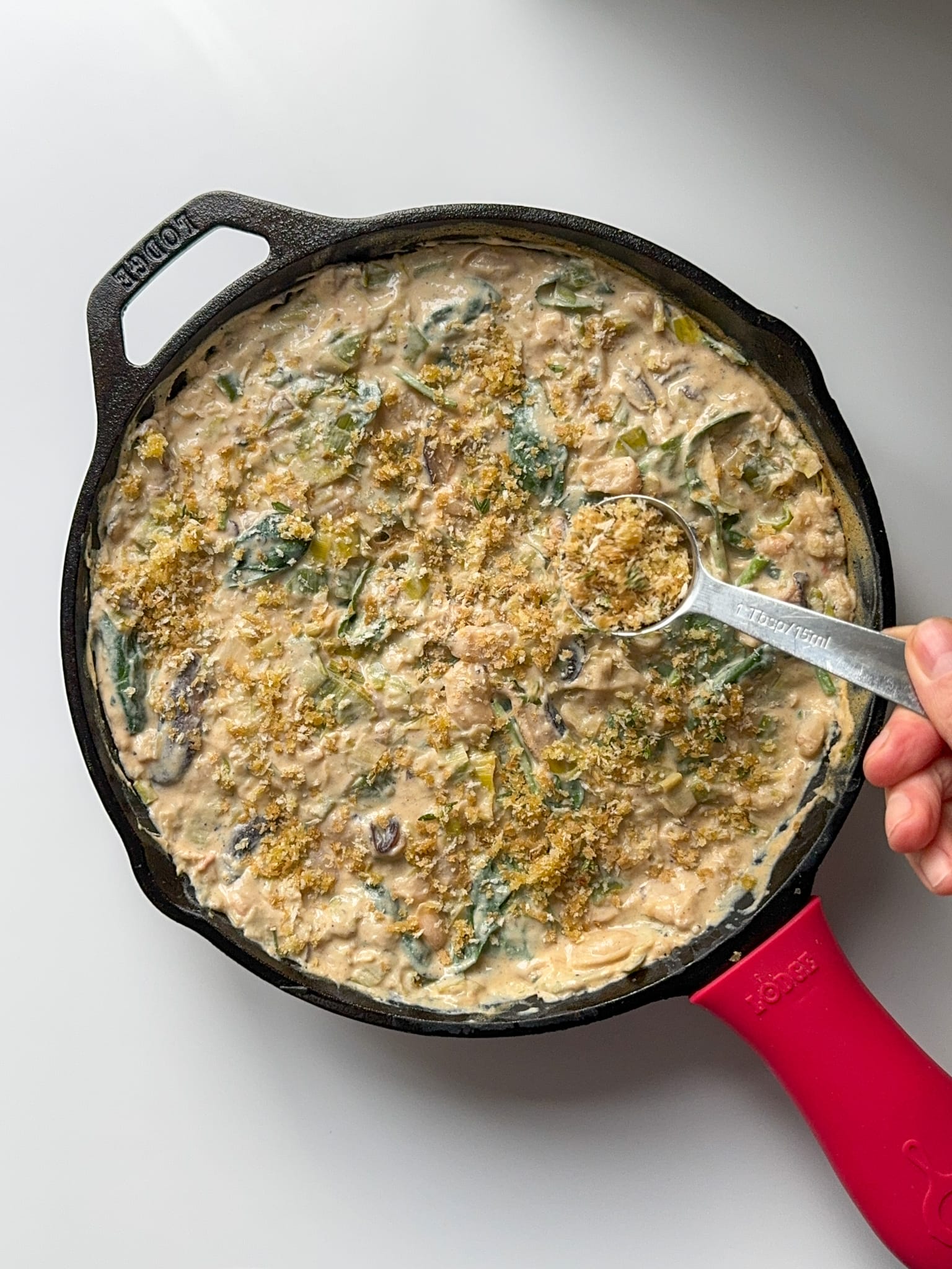 Topping the cheesy creamy mixture with the bread crumb and herbs mixture.