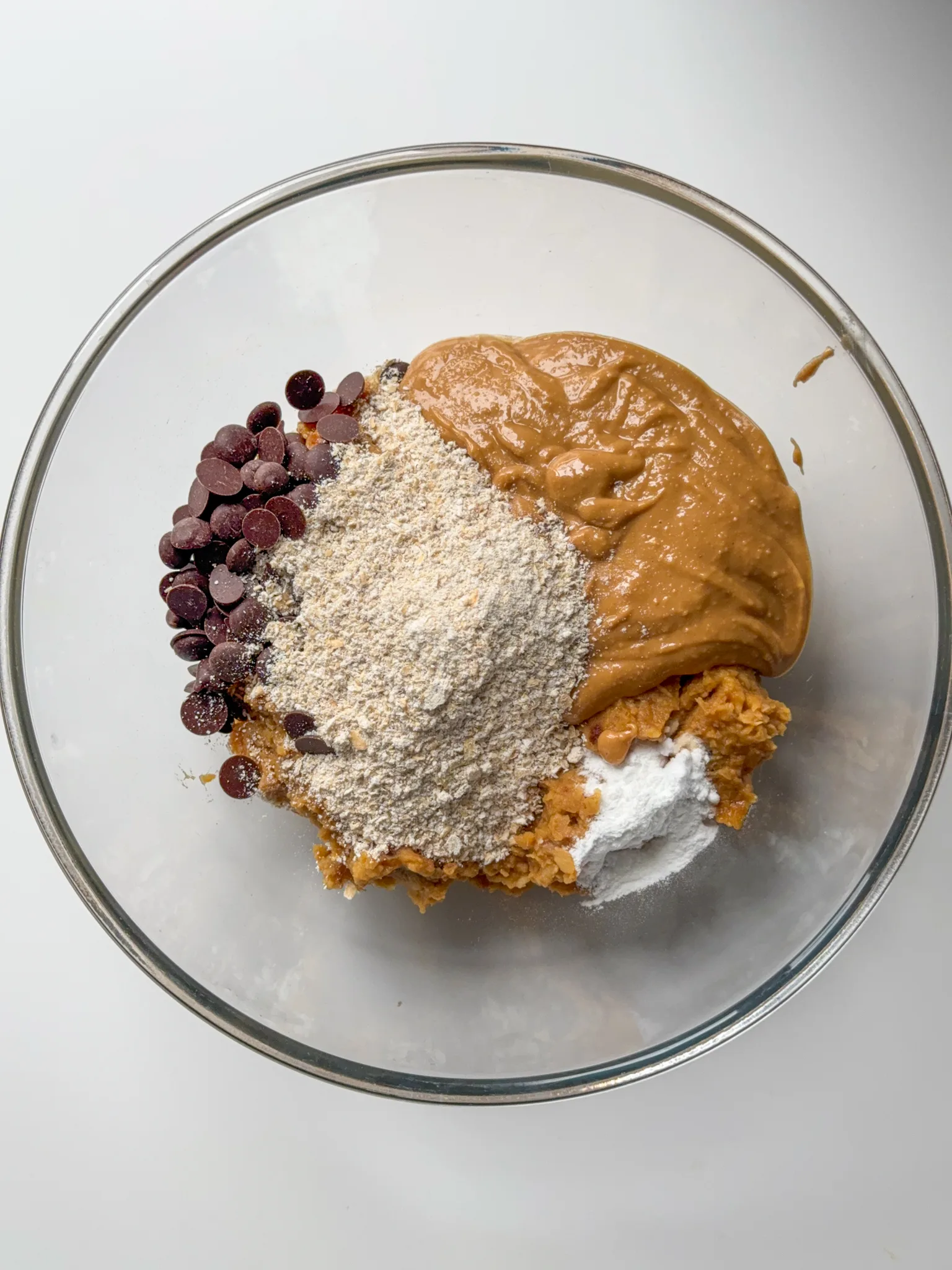Chickpea blend on a glass bowl with chocolate chips, oat flour, baking powder, baking soda and vanilla extract